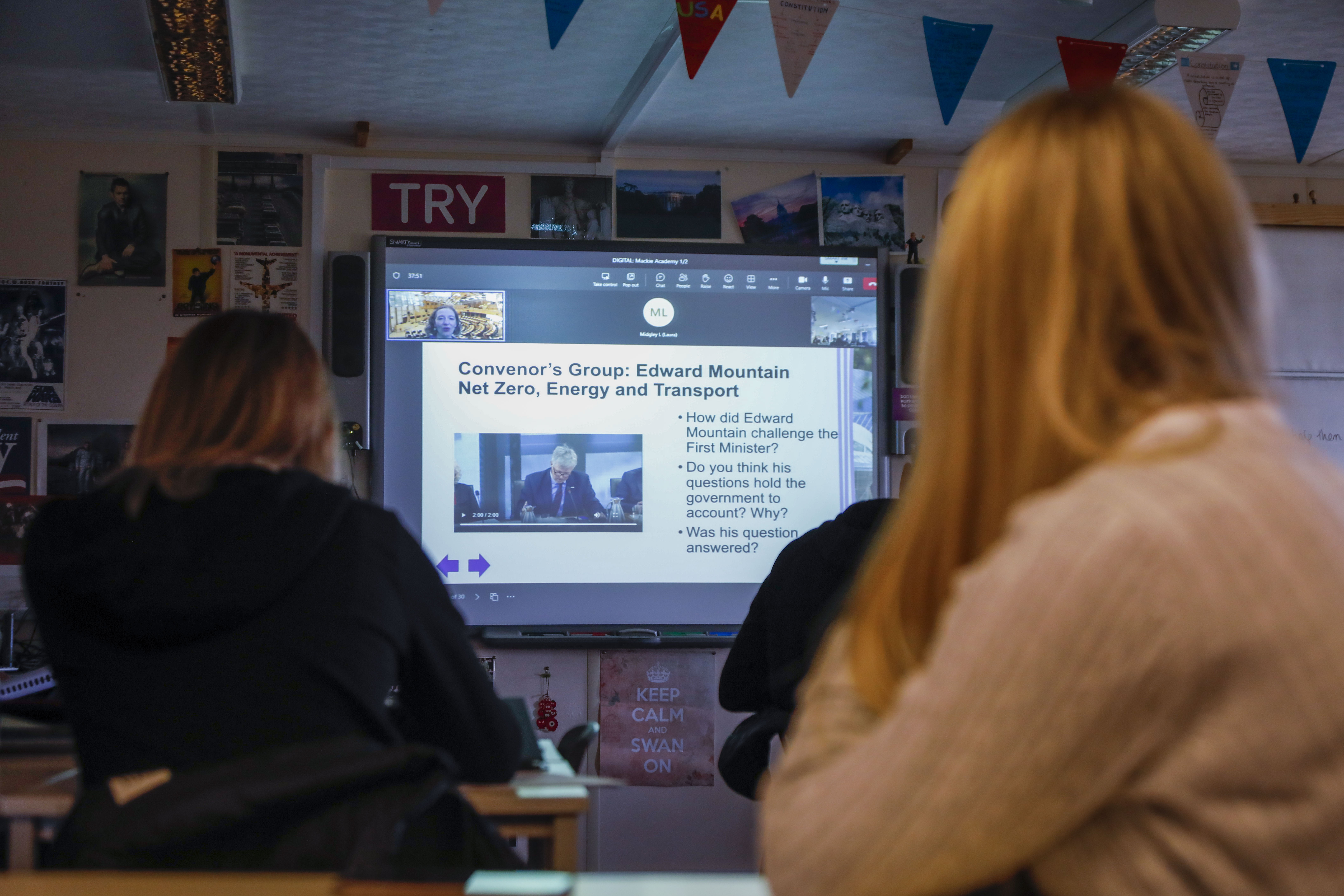 School pupils looking at a presentation on a screen at the front of a classroom