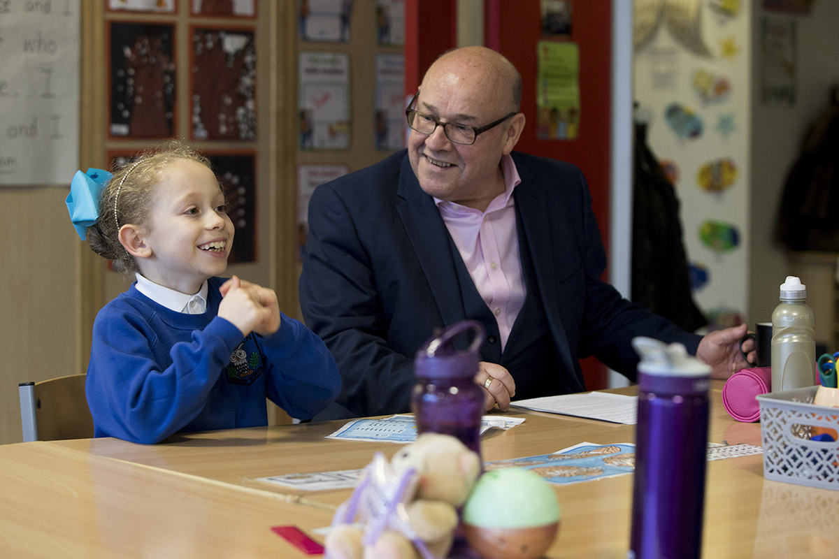  An MSP sits as a school desk with a young school child